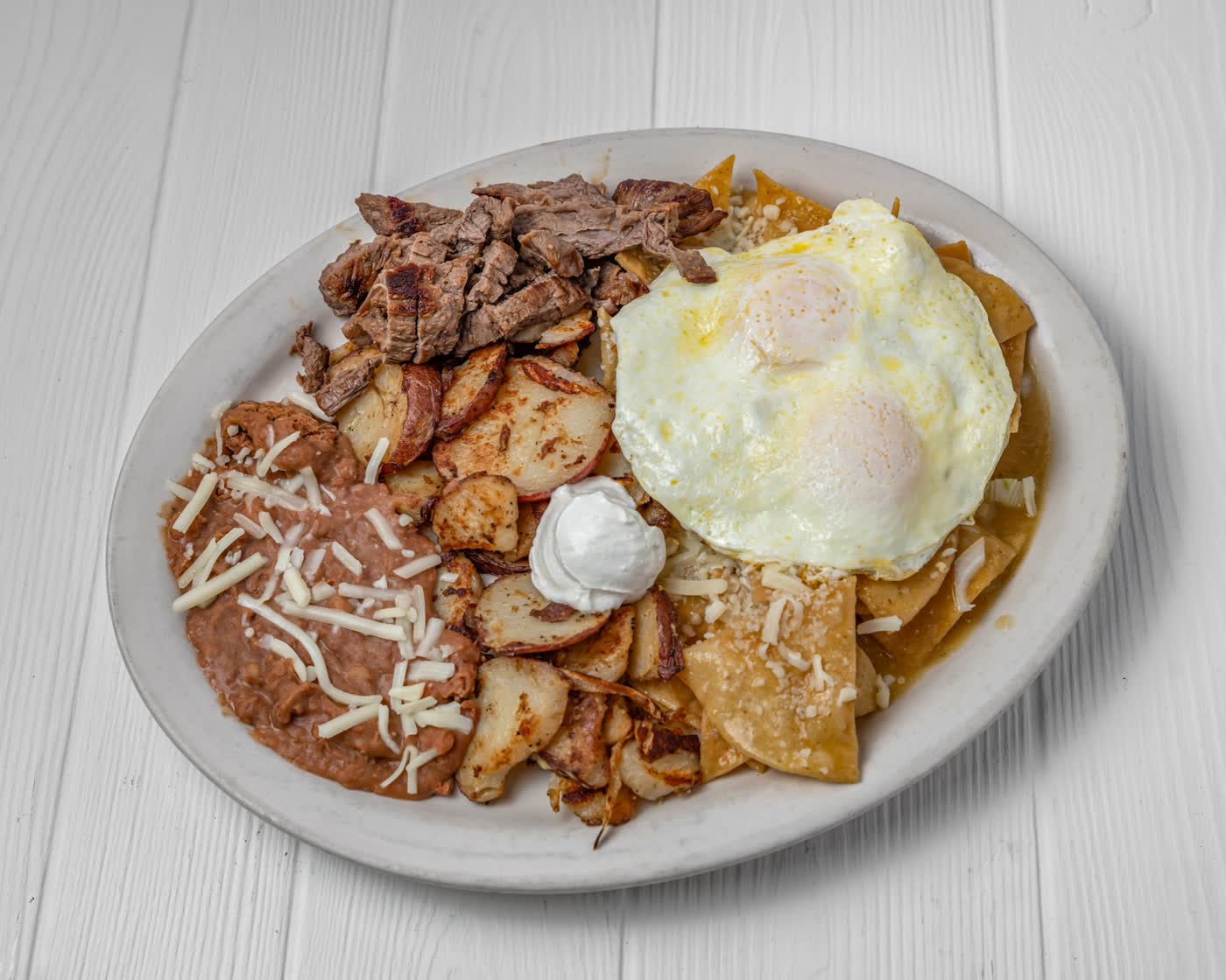 Chilaquiles with fajita steak, eggs, potatoes and beans
