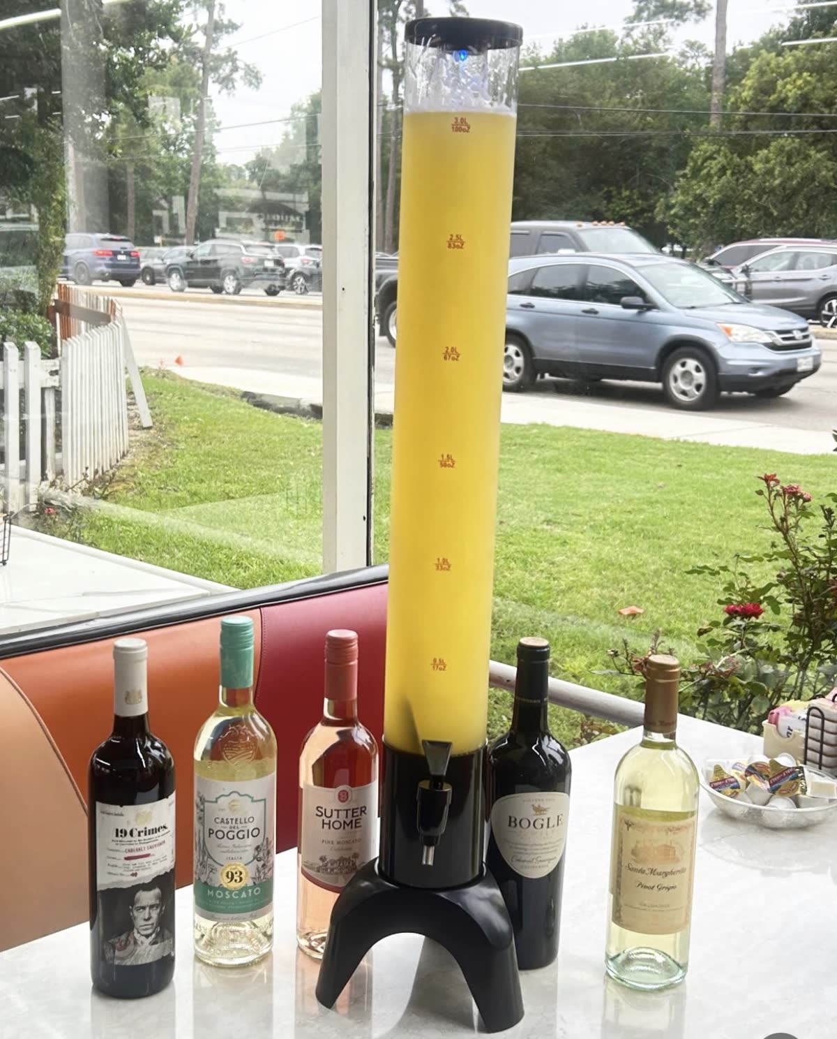 A 3-liter mimosa tower at a booth by the window, with bottles of red, white and moscato wine
